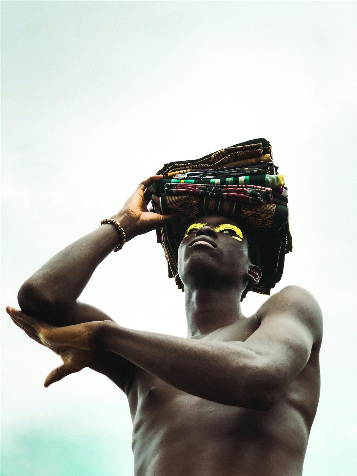 Portrait artistique d'un homme portant des tissus wax empilés sur la tête.