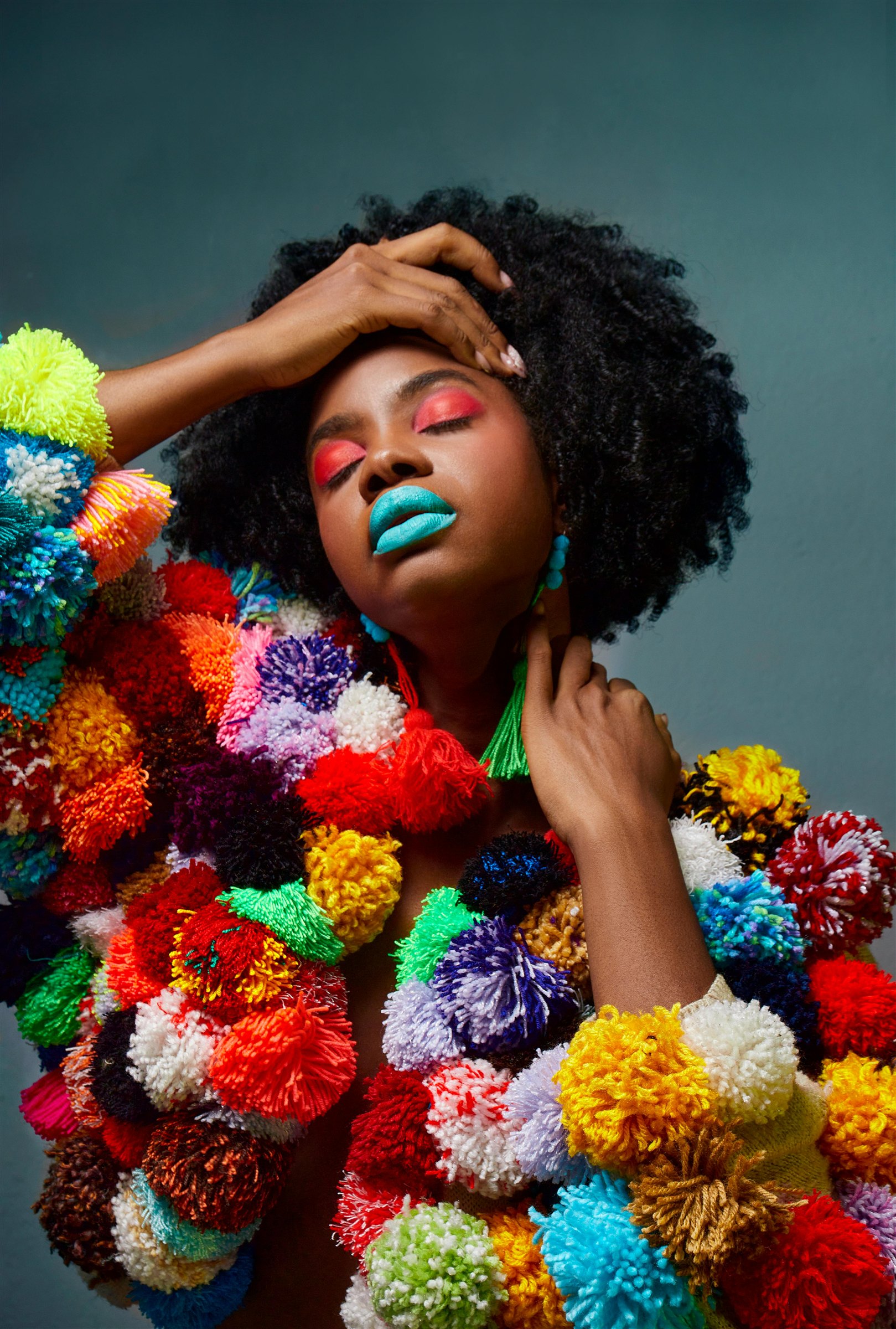 Portrait beauté audacieux, maquillage coloré et accessoires en pompons.