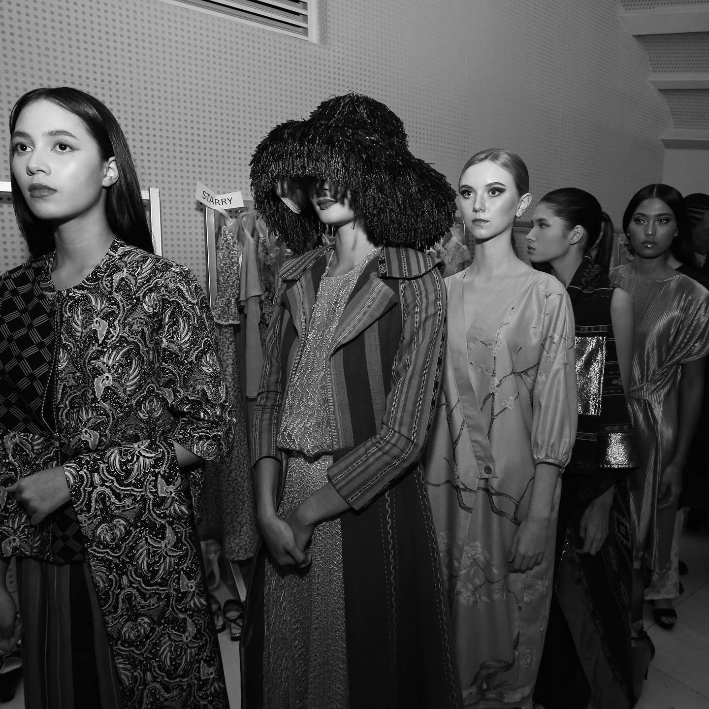 Mannequins en coulisses lors d'un essayage collectif avant un défilé.