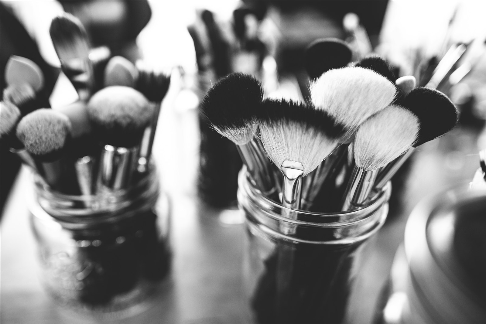 Pinceaux de maquillage rangés dans des pots en verre, coulisses.