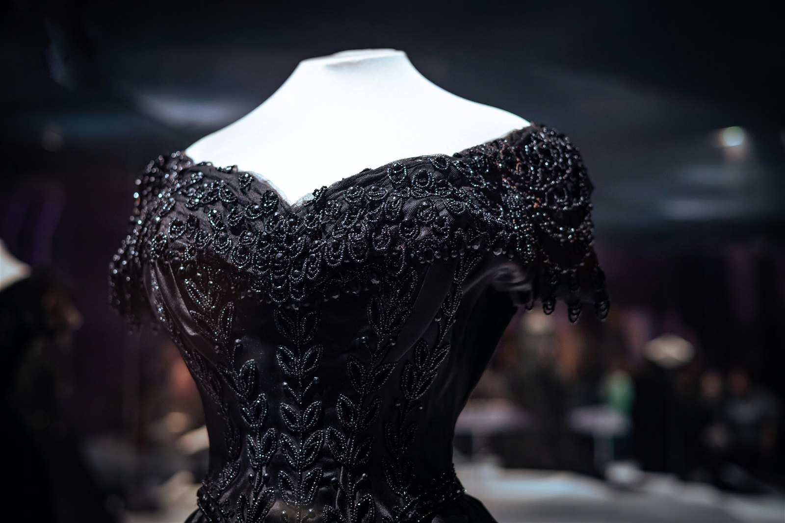 Détail d'un buste de couture noir perlé sur mannequin.